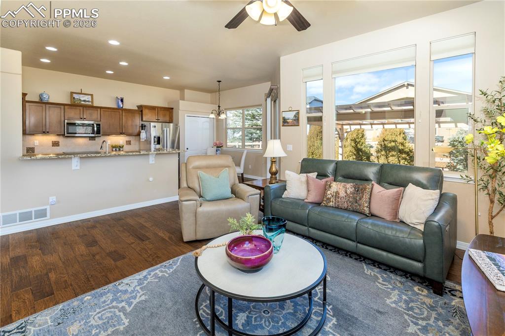 Image 21 of 50: Living area with ceiling fan, dark wood-style floors, and a chandelier