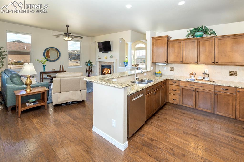 Image 27 of 50: Kitchen featuring wood finish cabinets, light stone counters, a warm lit fi