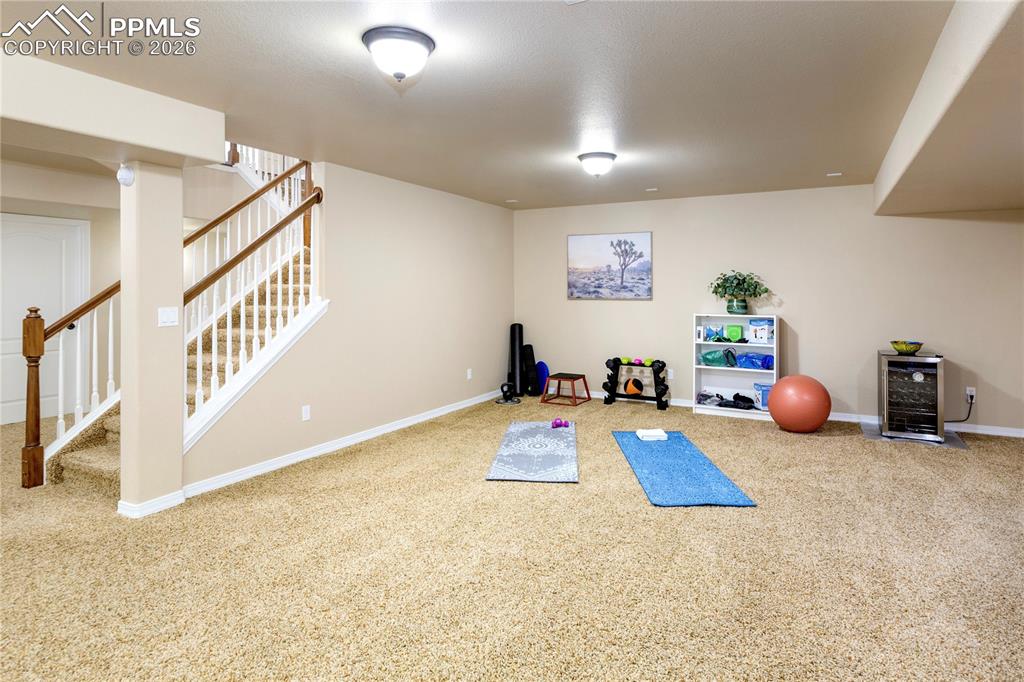 Image 39 of 50: Workout area with light carpet and wine cooler