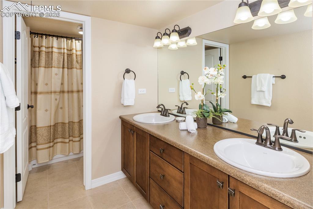 Image 42 of 50: Full bathroom features double vanity, tub/shower combination, maple cabinet