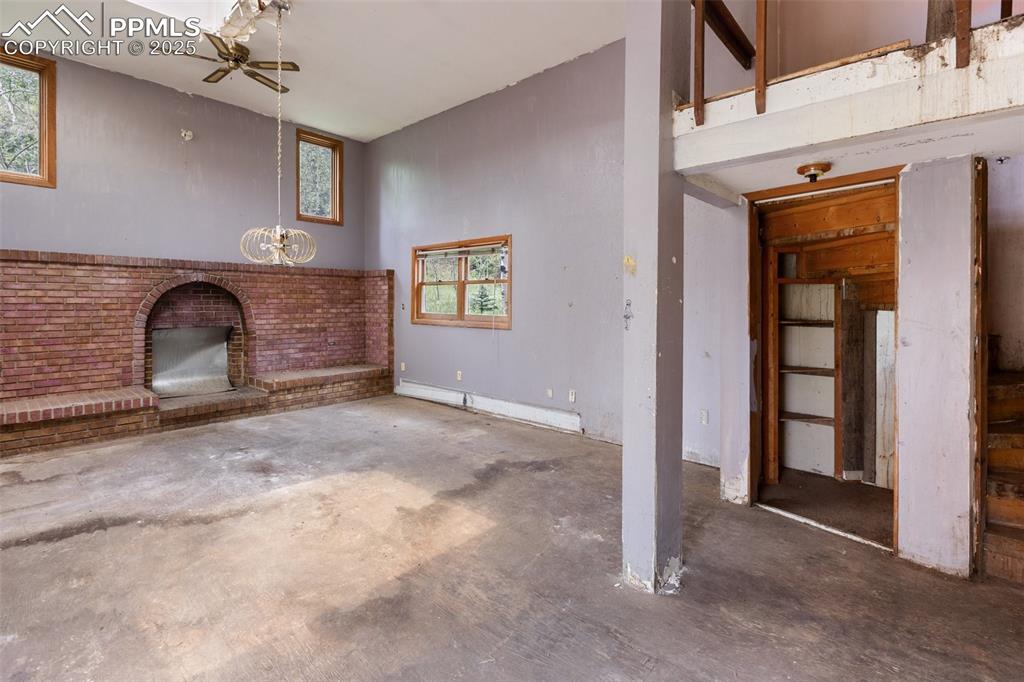 Image 12 of 36: Unfurnished living room featuring unfinished concrete flooring, a ceiling f