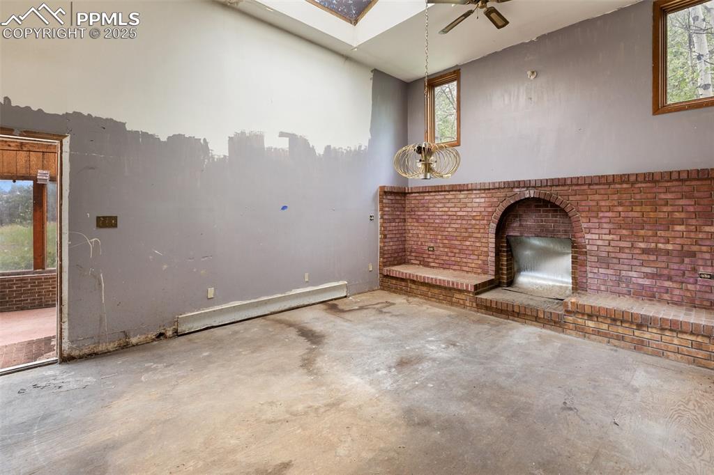 Image 13 of 36: Unfurnished living room with concrete flooring, ceiling fan, baseboard heat