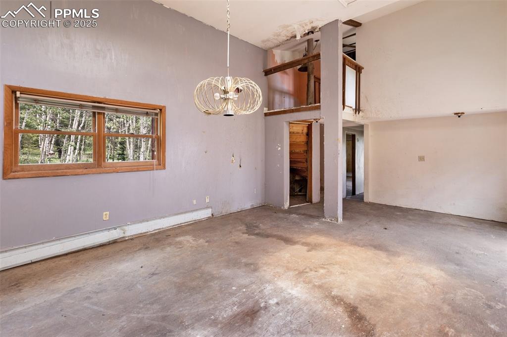 Image 14 of 36: Spare room featuring concrete floors, a chandelier, a baseboard heating uni