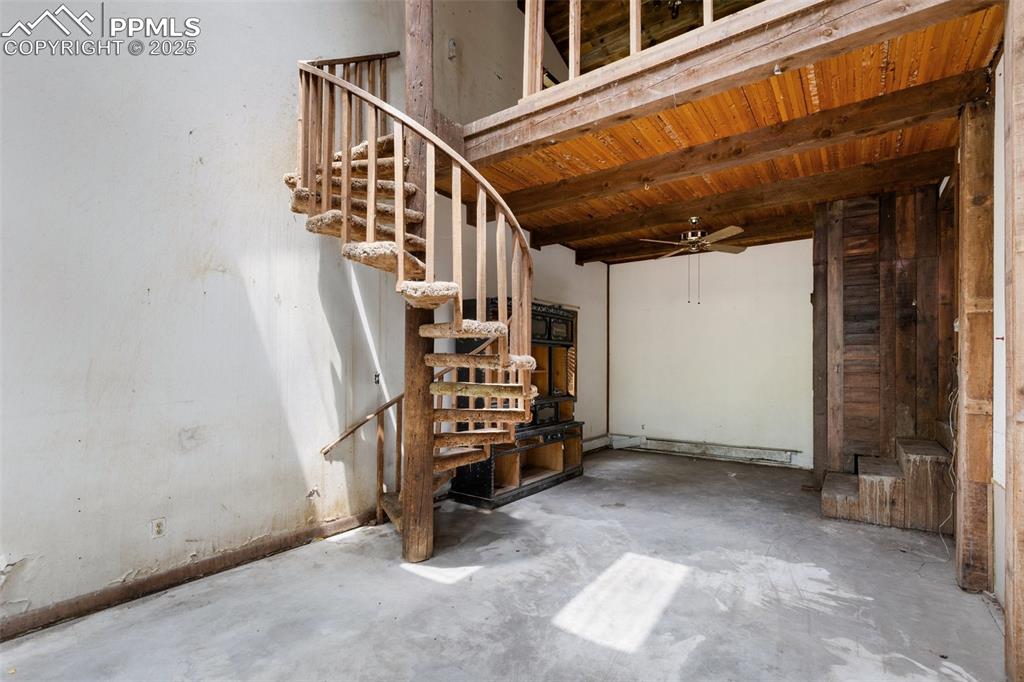 Image 15 of 36: Basement with a ceiling fan, stairs, wood ceiling, and baseboard heating