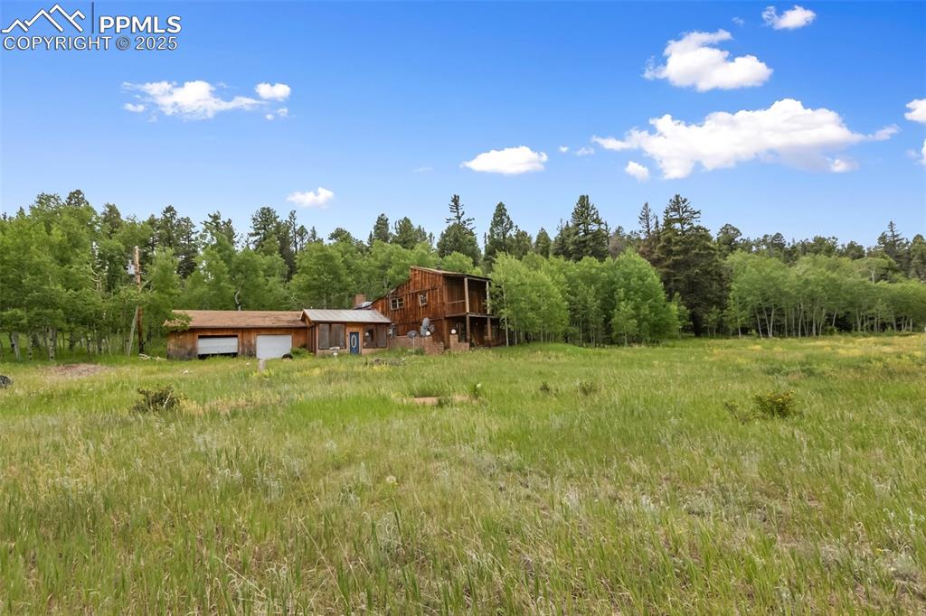 Image 2 of 36: View of yard featuring a garage and a view of trees
