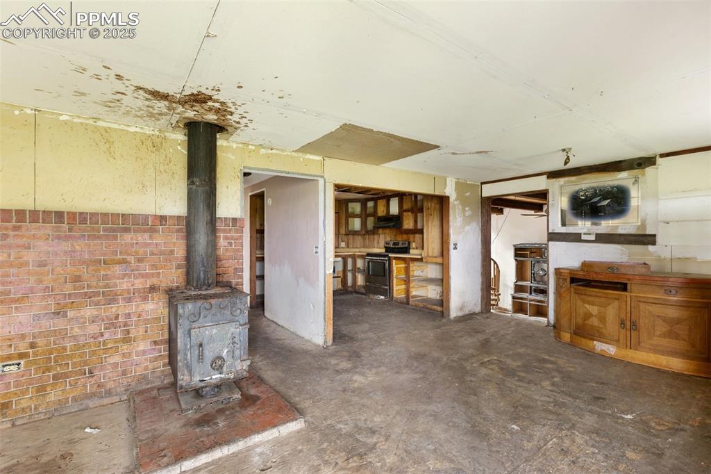 Image 6 of 36: Unfurnished living room featuring concrete flooring and a wood stove