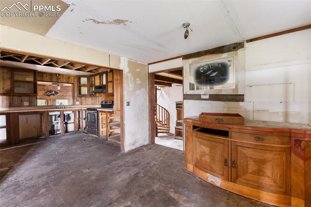 Image 7 of 36: Kitchen with stainless steel range with electric stovetop, brown cabinets,