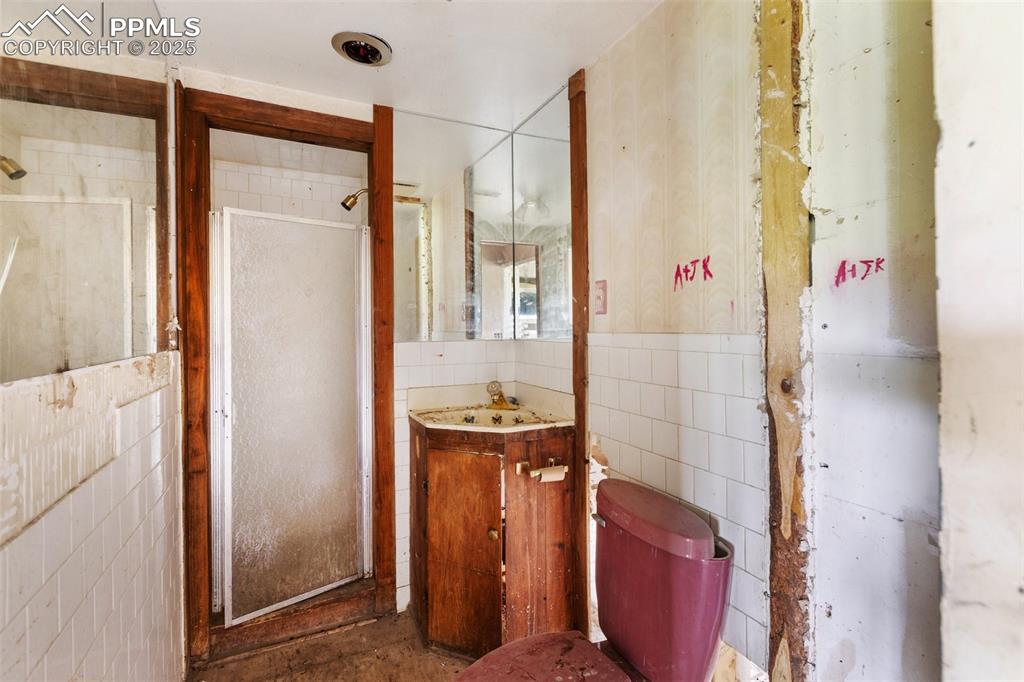 Image 9 of 36: Bathroom featuring vanity, a shower stall, tile walls, and wainscoting