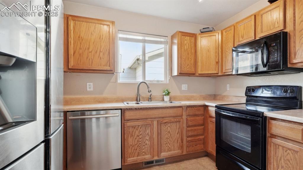 Image 8 of 28: Kitchen with black and stainless steel appliances, light countertops, and a