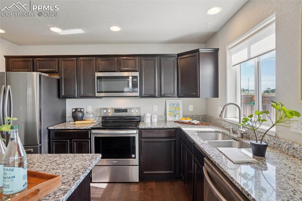 Image 11 of 46: Kitchen with appliances with stainless steel finishes, dark brown cabinetry
