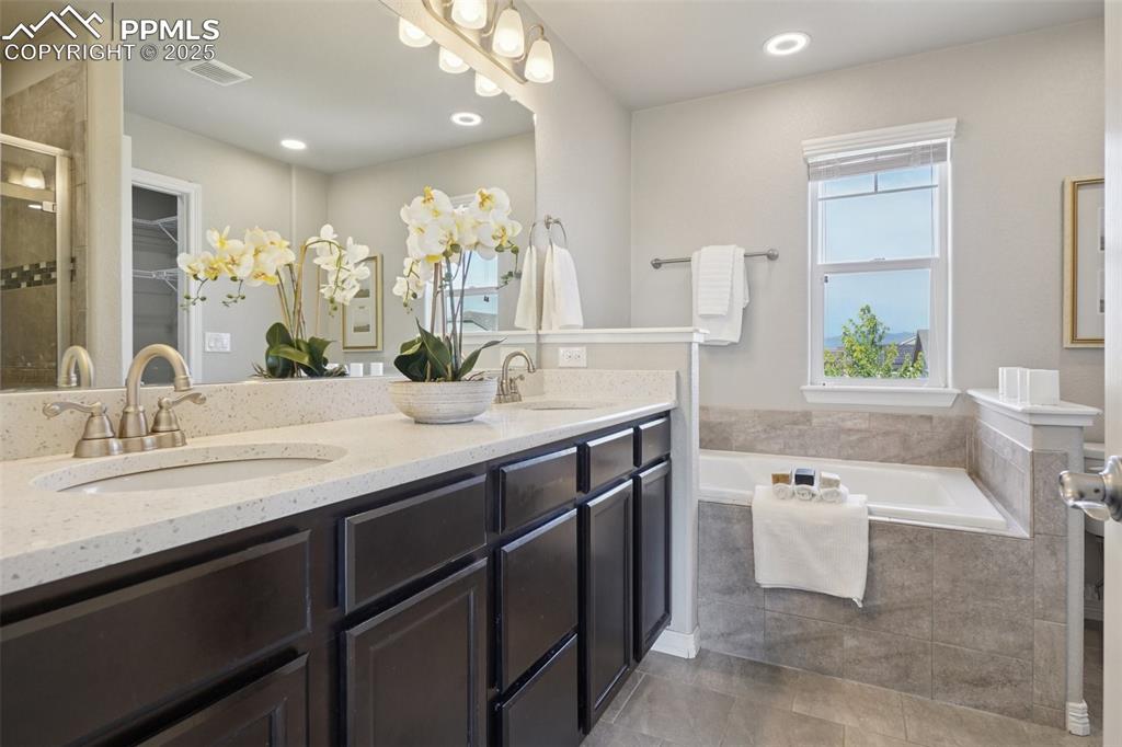 Image 15 of 46: Bathroom featuring double vanity, a bath, a stall shower, recessed lighting