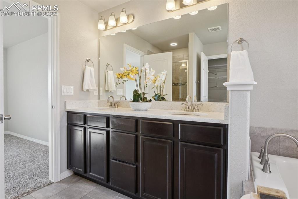 Image 16 of 46: Full bath featuring double vanity, a stall shower, a garden tub, and tile p