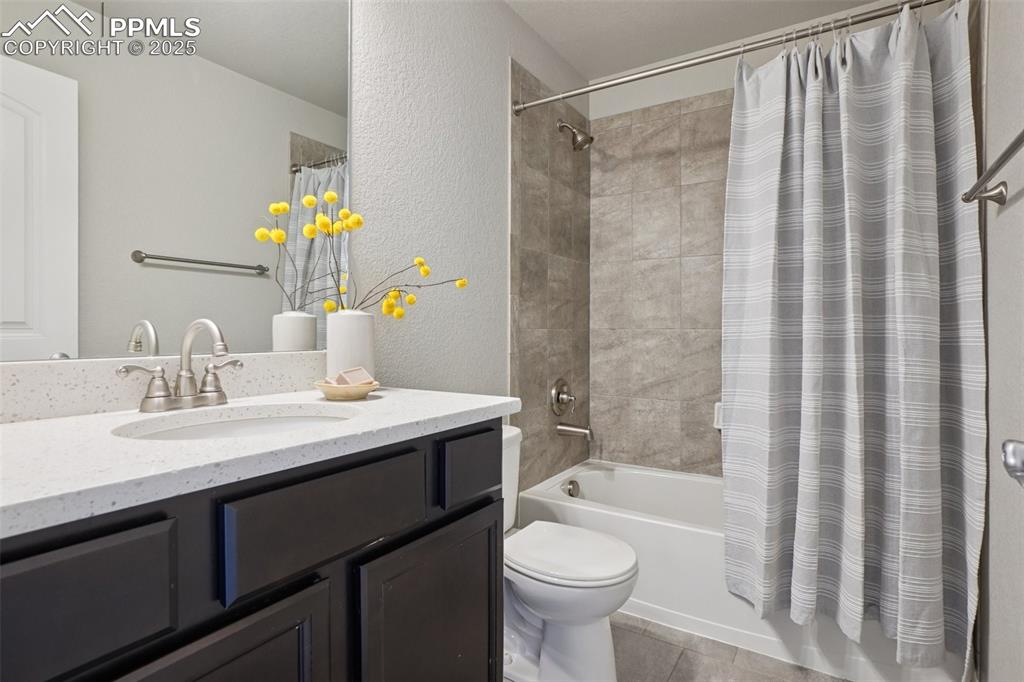 Image 23 of 46: Full bathroom featuring vanity, shower / bath combo, a textured wall, and t