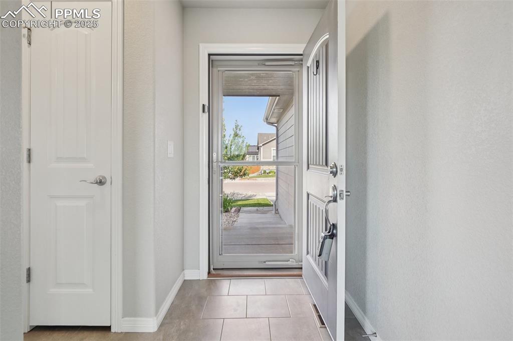 Image 33 of 46: Doorway to outside with baseboards and tile patterned flooring
