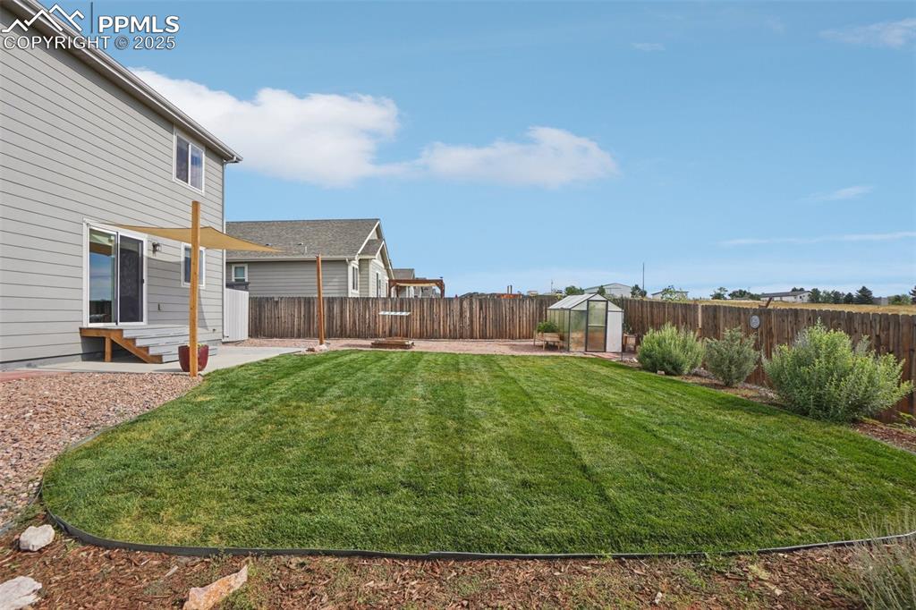 Image 42 of 46: Fenced backyard with an exterior structure, entry steps, an outbuilding, an