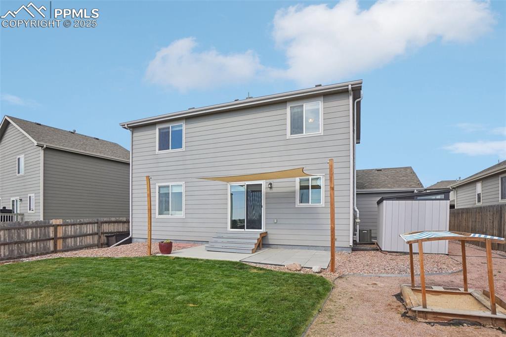 Image 43 of 46: Rear view of property with entry steps, a fenced backyard, and an outdoor s