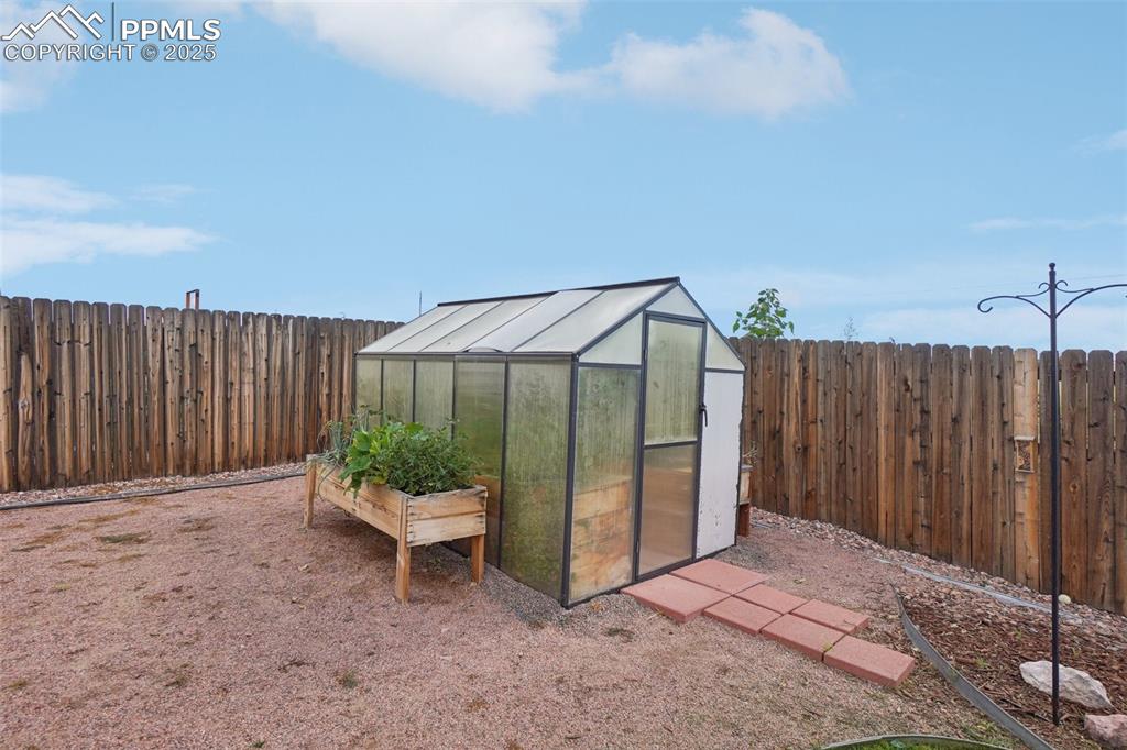 Image 44 of 46: View of greenhouse featuring a fenced backyard