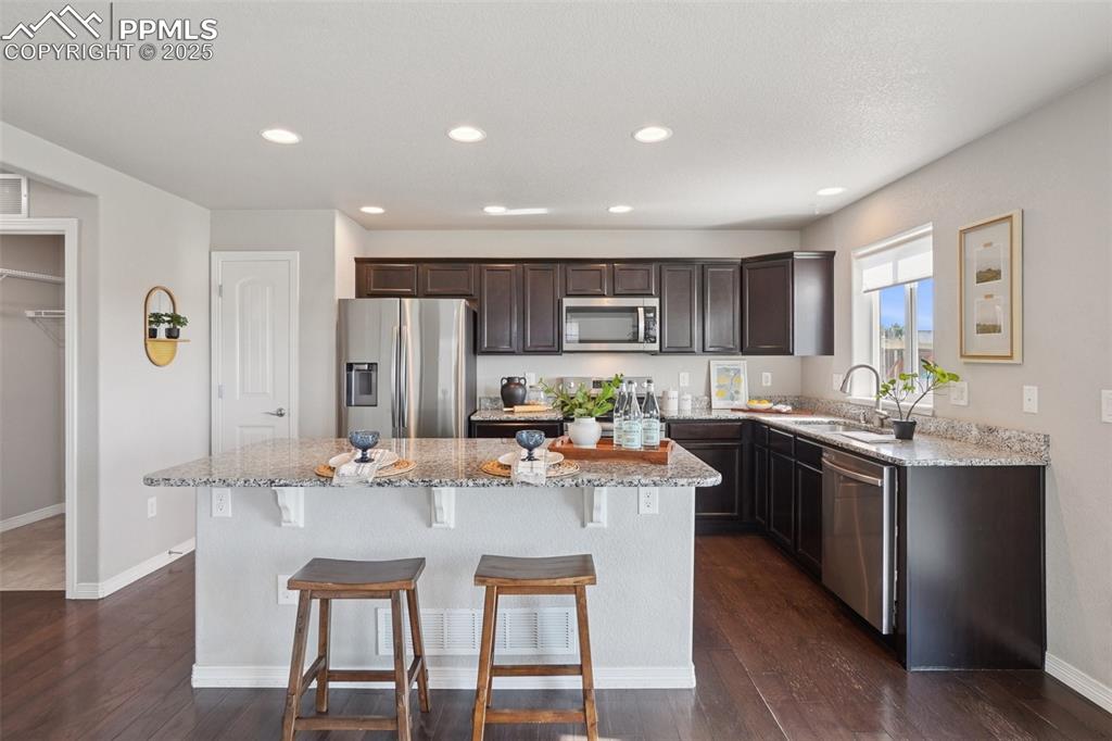 Image 8 of 46: Kitchen featuring a kitchen island, stainless steel appliances, light stone