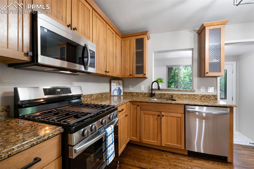 Image 12 of 33: Kitchen featuring appliances with stainless steel finishes, dark stone coun