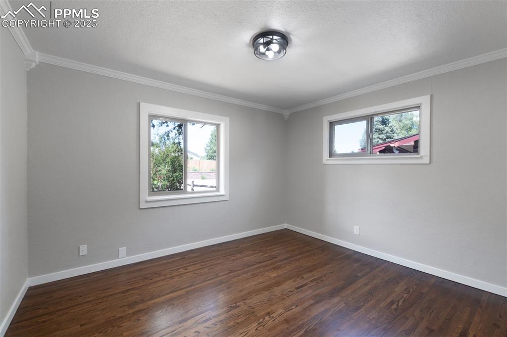 Image 14 of 33: Unfurnished room with crown molding, healthy amount of natural light, dark 