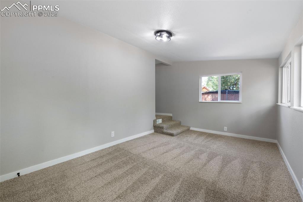 Image 18 of 33: Unfurnished room with light colored carpet and stairs