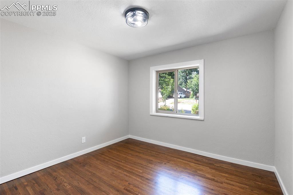 Image 21 of 33: Empty room with dark wood-type flooring and a textured ceiling