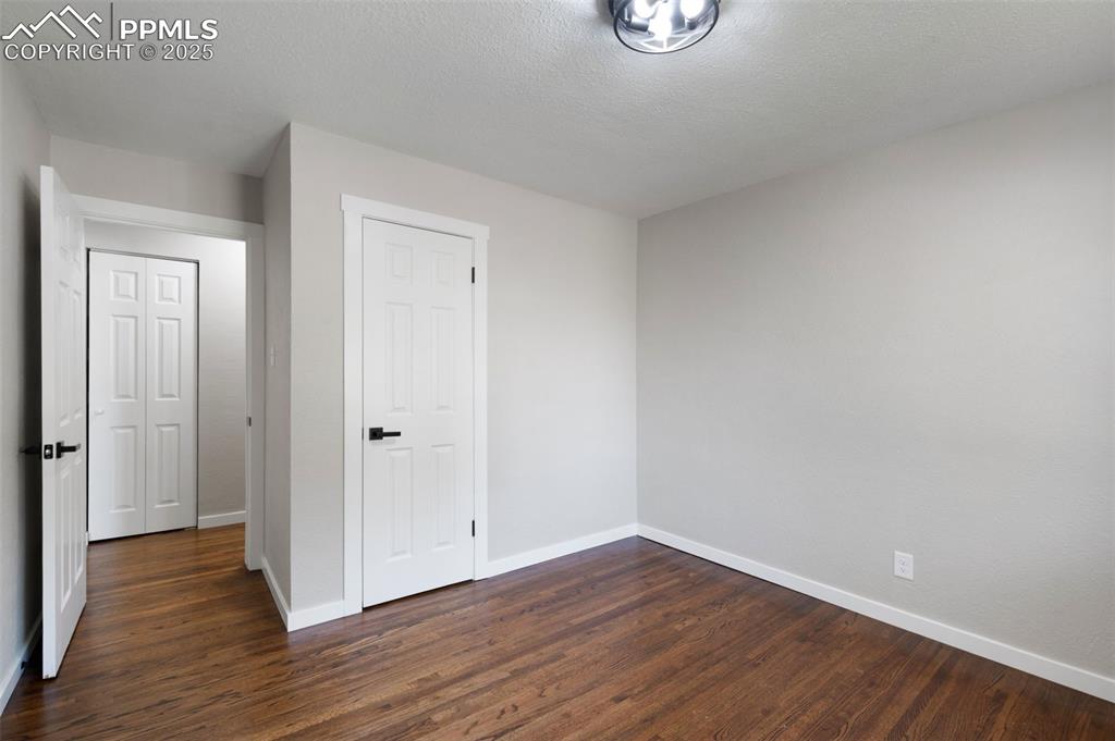 Image 22 of 33: Unfurnished bedroom featuring dark wood-type flooring and a textured ceilin