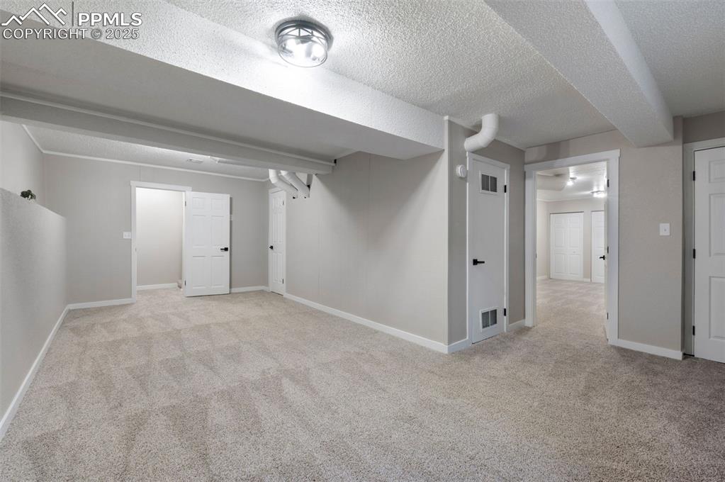 Image 24 of 33: Finished basement featuring light colored carpet and a textured ceiling