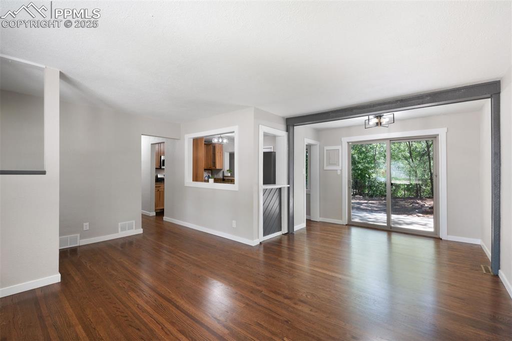 Image 5 of 33: Empty room featuring dark wood-style floors and a chandelier