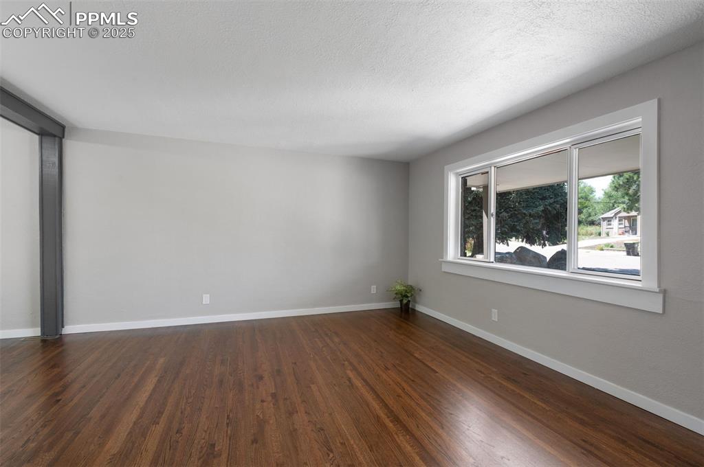 Image 7 of 33: Unfurnished room featuring dark wood-style floors and a textured ceiling