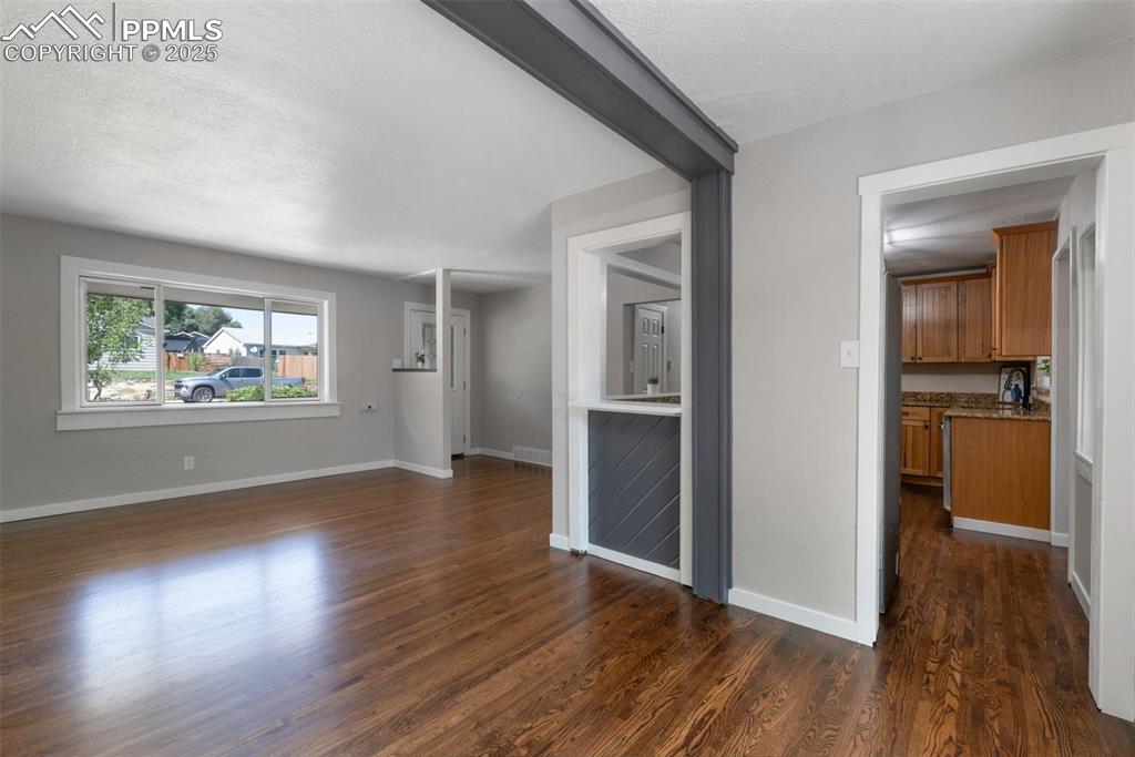 Image 9 of 33: Unfurnished living room with dark wood-type flooring and a textured ceiling