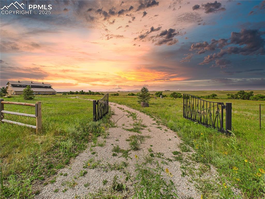 Image 30 of 50: Gated Entry Drive – A private gravel road leads through an iron gate to the