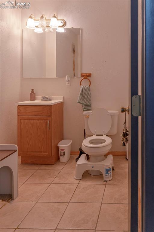 Image 10 of 23: Half bathroom with vanity, light tile patterned floors, and a textured wall