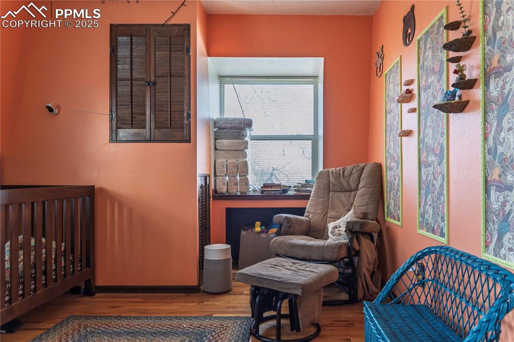 Image 12 of 23: Bedroom with a crib, wood finished floors, and a textured ceiling
