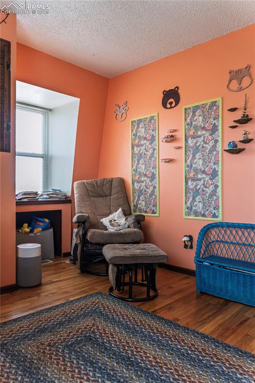 Image 15 of 23: Living area with wood finished floors and a textured ceiling