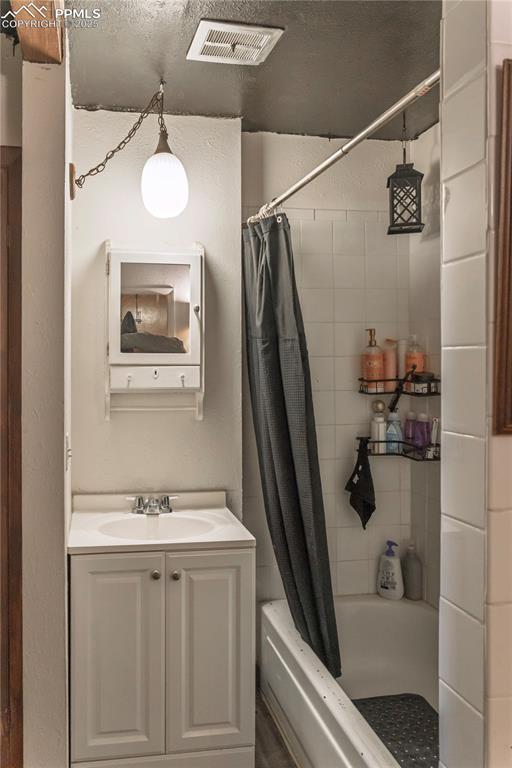 Image 17 of 23: Bathroom featuring vanity, a textured wall, and shower / bath combo