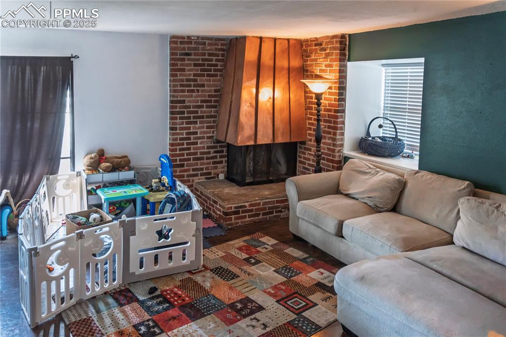 Image 5 of 23: Living room featuring a brick fireplace and healthy amount of natural light