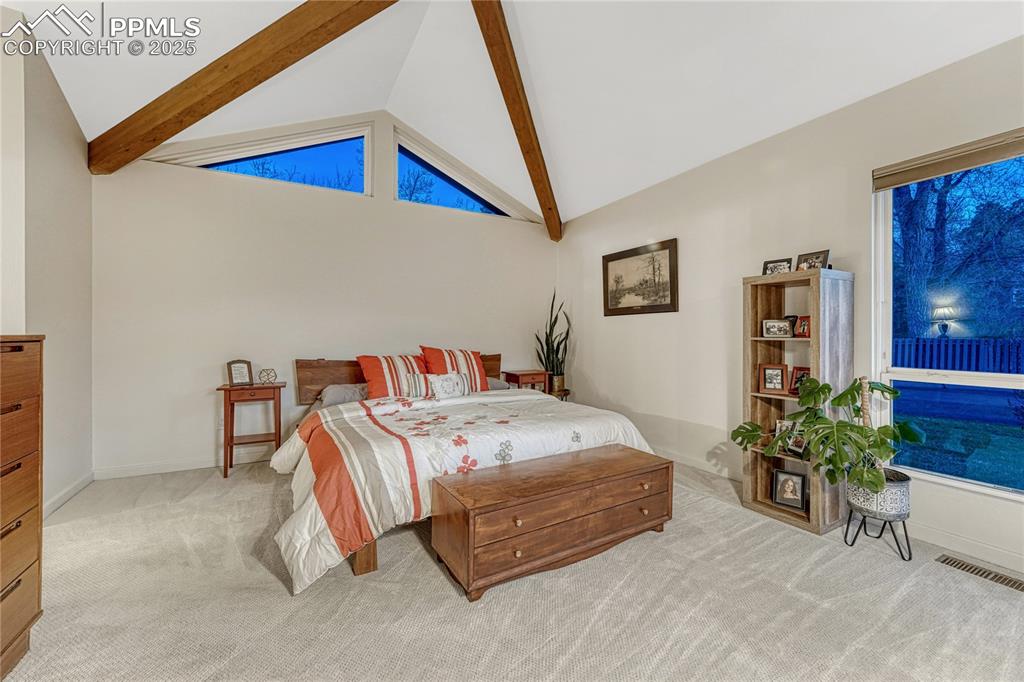 Image 4 of 36: Master bedroom with vaulted and beamed ceilings.