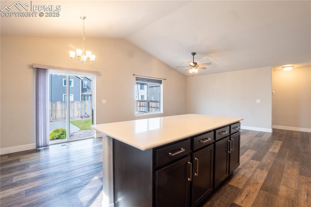 Image 17 of 35: Kitchen featuring dark wood-type flooring, lofted ceiling, pendant lighting