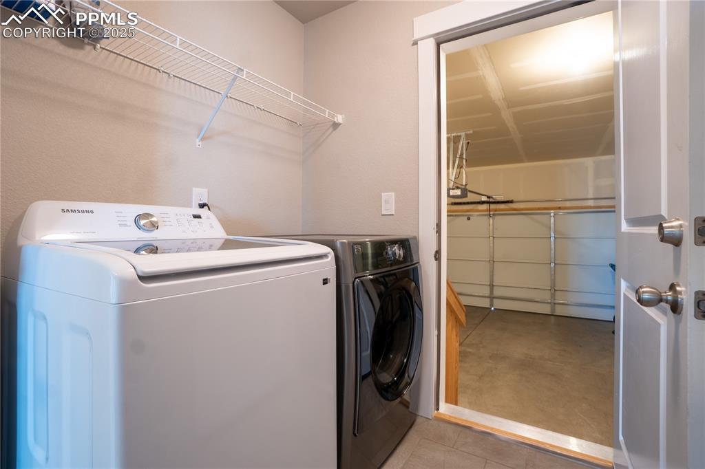 Image 18 of 35: Washroom featuring concrete flooring and washer and clothes dryer