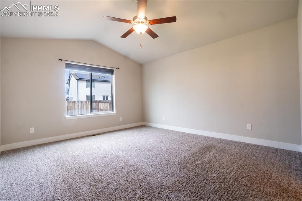 Image 19 of 35: Carpeted empty room featuring lofted ceiling and ceiling fan