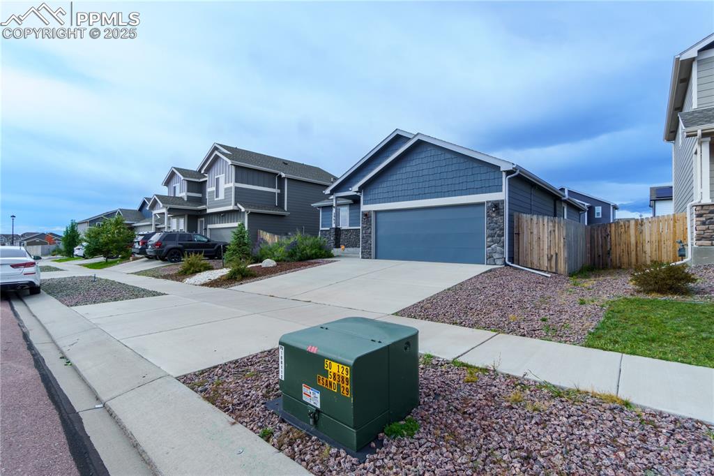 Image 2 of 35: Craftsman-style house featuring stone siding, driveway, a residential view,