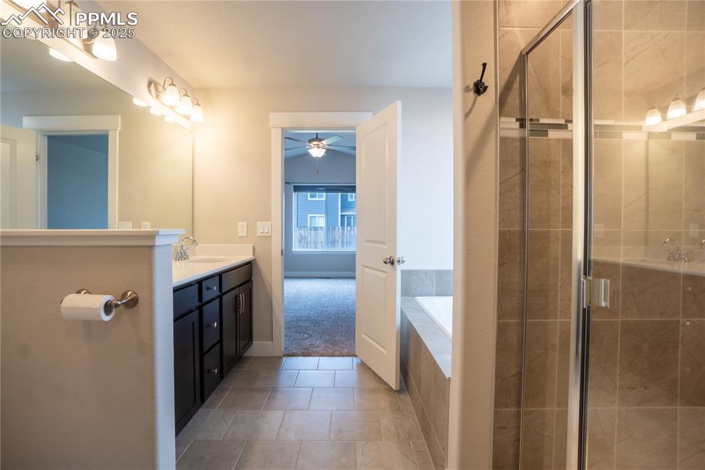 Image 22 of 35: Bathroom featuring vanity, a garden tub, a stall shower, light tile pattern