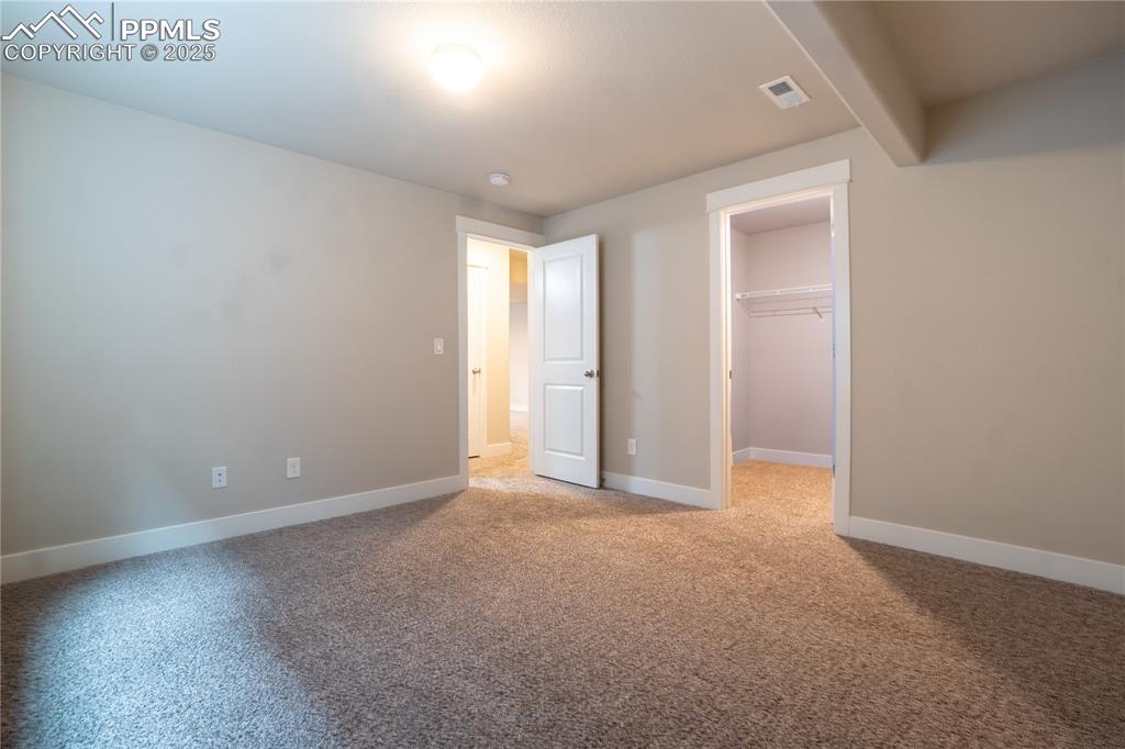 Image 27 of 35: Unfurnished bedroom with a walk in closet and light colored carpet