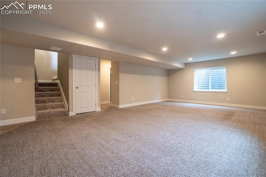 Image 29 of 35: Below grade area with stairs, light colored carpet, and recessed lighting