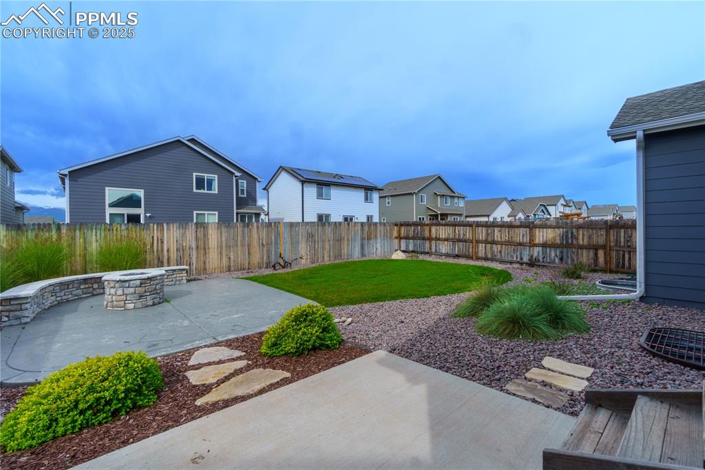 Image 32 of 35: Fenced backyard with a patio area, a fire pit, and a residential view