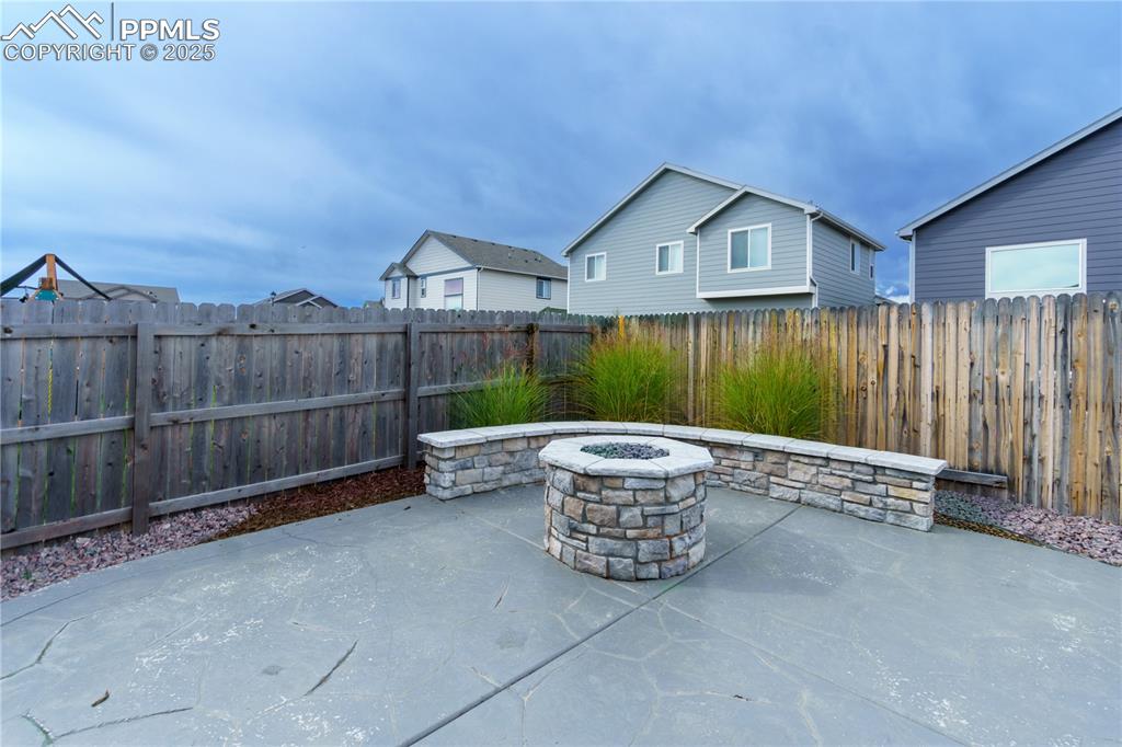 Image 33 of 35: Fenced backyard featuring a patio area and an outdoor fire pit