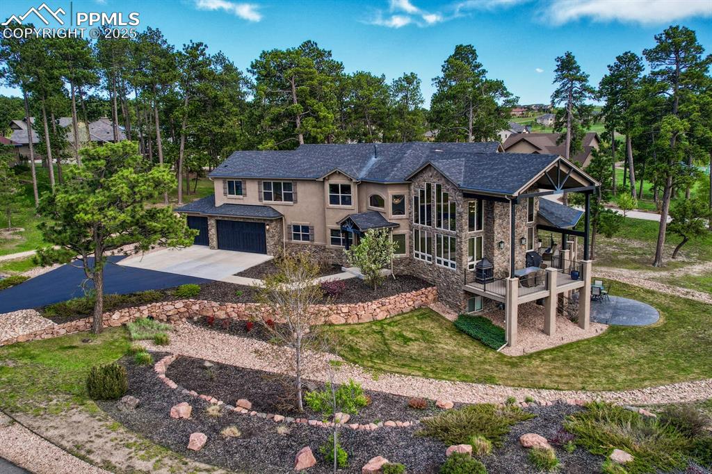 Caption: View of front facade with concrete driveway, stone siding, stucco siding, an attached garage, and a 