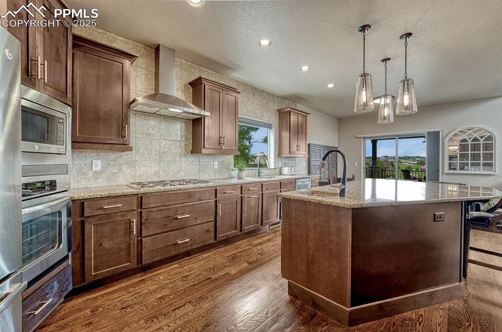 Image 11 of 50: Kitchen featuring appliances with stainless steel finishes, wall chimney ra