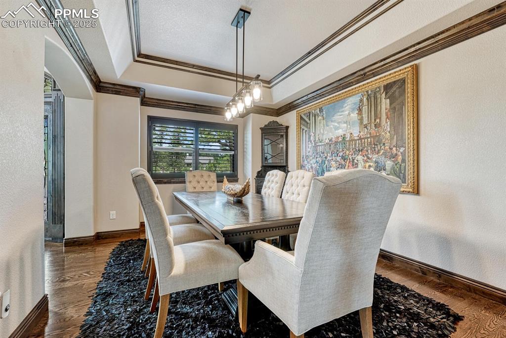 Image 13 of 50: Dining room with crown molding, wood finished floors, and baseboards